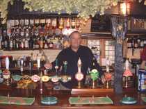 Tom the Landlord behind the bar at The Red Cow